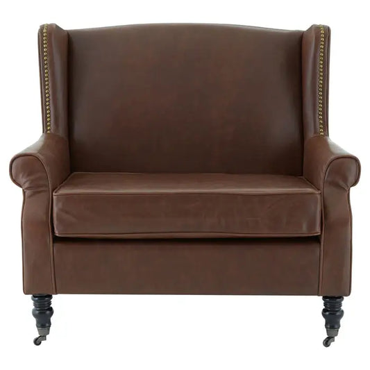 Brown faux leather wing chair with gold studs and carved legs 